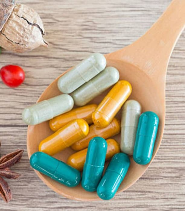 Colorful capsules on a wooden spoon with a wooden background