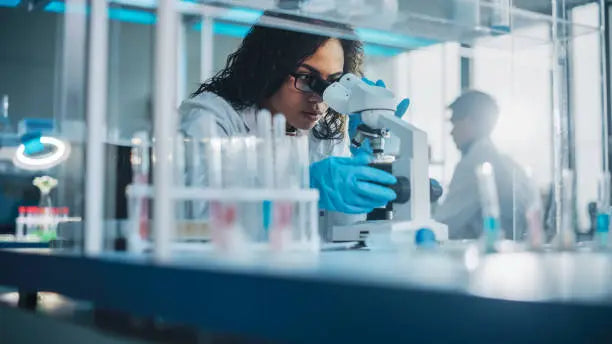 Chemist using a microscope in a Lords healthcare laboratory